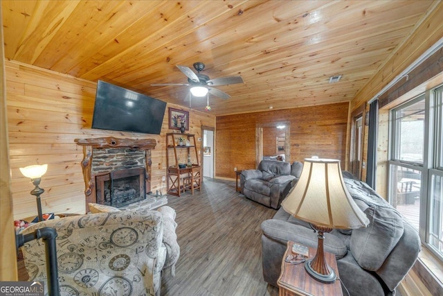 living area featuring a fireplace, wood finished floors, wood ceiling, and wooden walls