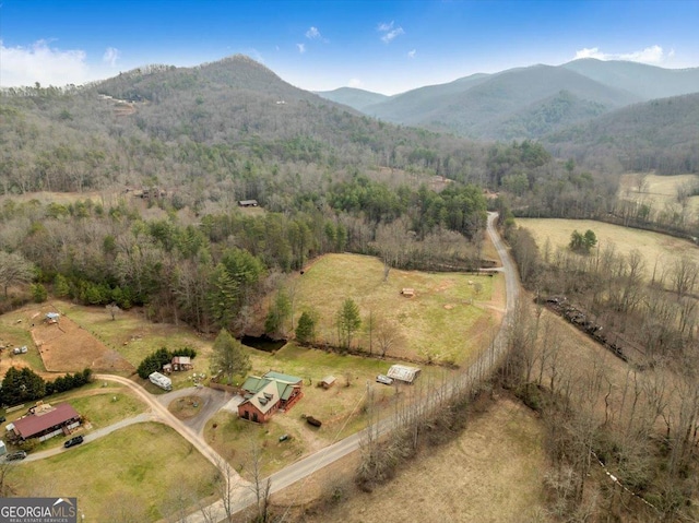 birds eye view of property featuring a rural view, a mountain view, and a wooded view