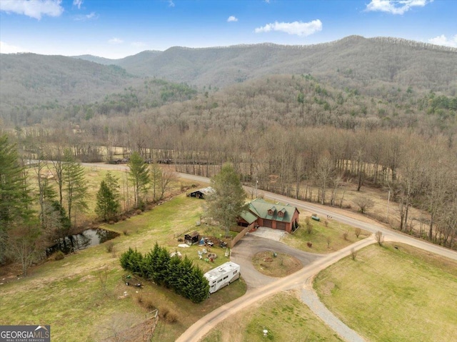 drone / aerial view featuring a mountain view, a view of trees, and a rural view