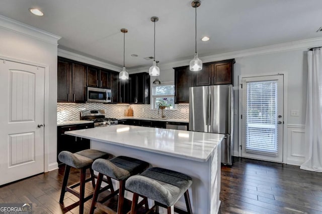 kitchen with appliances with stainless steel finishes, dark wood-style flooring, crown molding, and a kitchen island