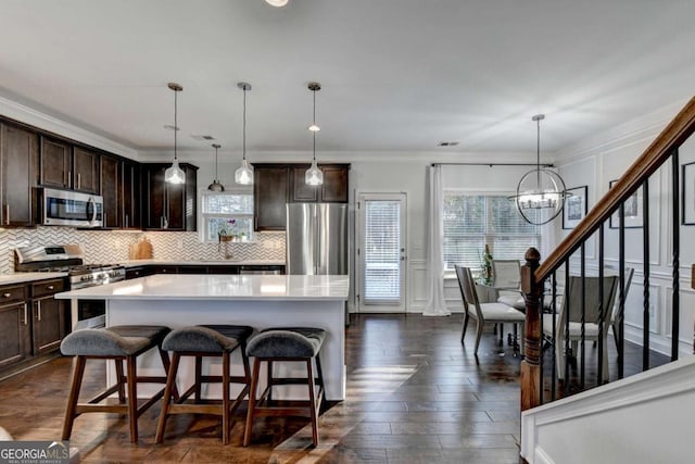 kitchen with stainless steel appliances, dark brown cabinets, decorative backsplash, and a decorative wall