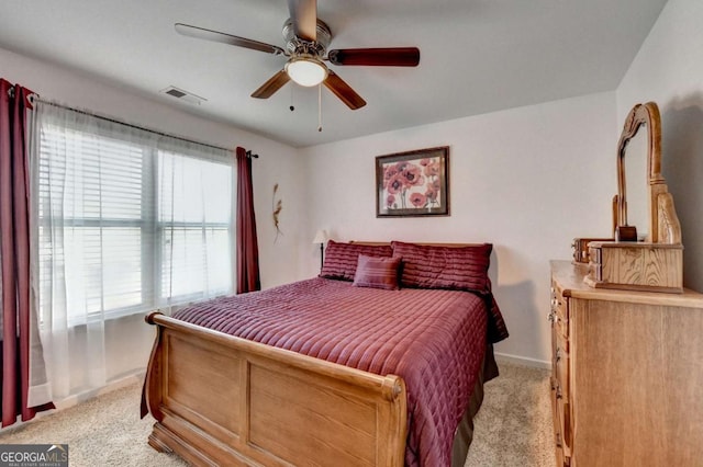 bedroom featuring light colored carpet, ceiling fan, visible vents, and baseboards