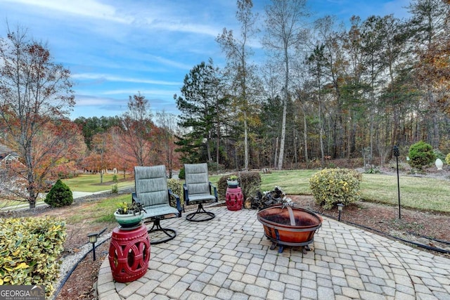 view of patio / terrace with a fire pit and a forest view