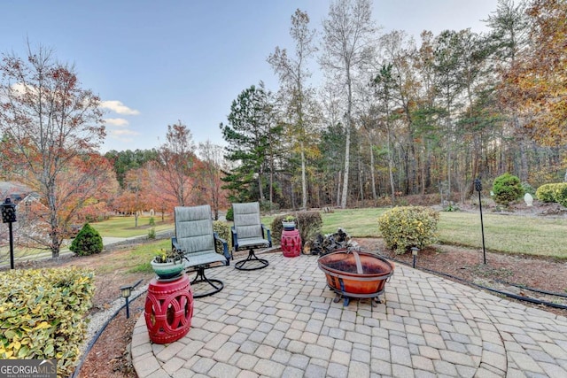 view of patio / terrace with a fire pit and a view of trees