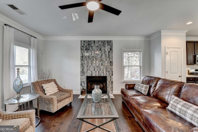 living room with ornamental molding, dark wood finished floors, visible vents, and a healthy amount of sunlight