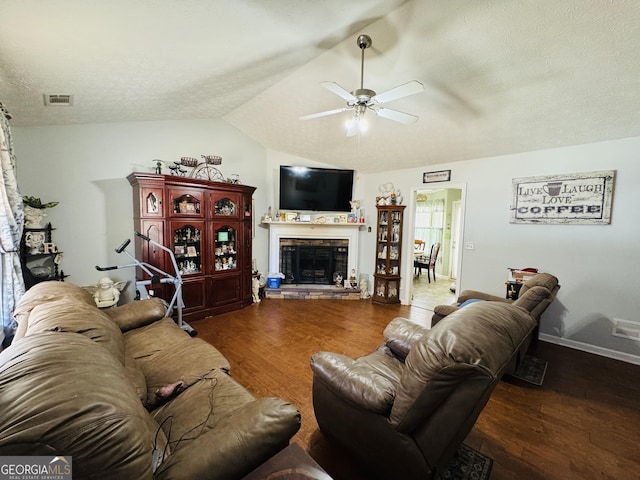 living area featuring lofted ceiling, a textured ceiling, a fireplace, wood finished floors, and visible vents