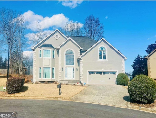 traditional-style house featuring concrete driveway, an attached garage, and stucco siding