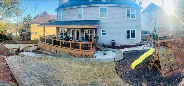 back of property featuring fence, a porch, and a playground