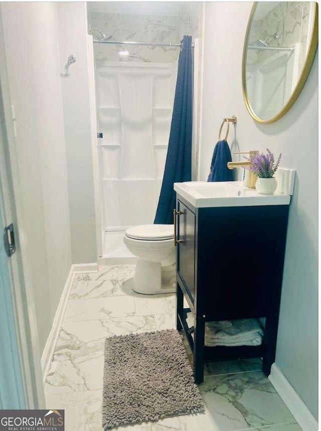 bathroom featuring marble finish floor, a shower stall, vanity, and baseboards