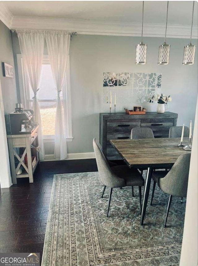 dining space featuring baseboards, wood finished floors, and crown molding