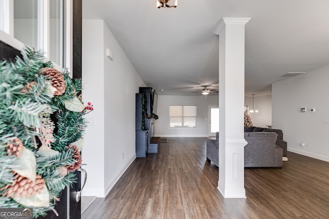 entryway featuring decorative columns, baseboards, wood finished floors, and ceiling fan with notable chandelier