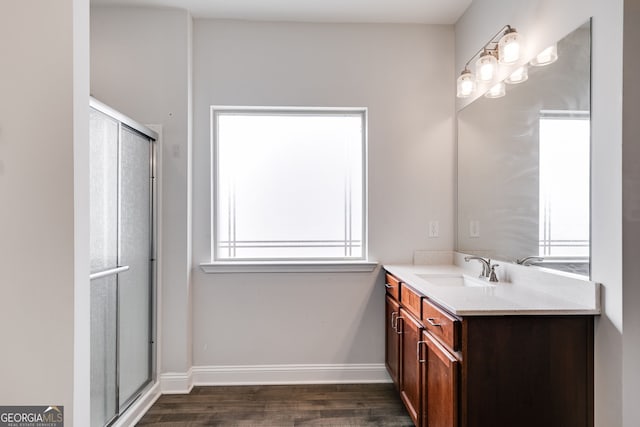 full bath with wood finished floors, an enclosed shower, vanity, and baseboards