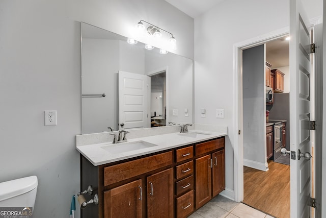 full bath with double vanity, tile patterned flooring, a sink, and toilet