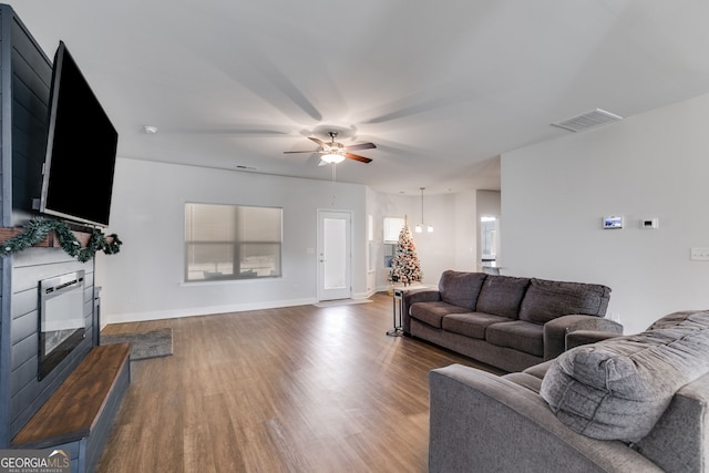 living area with a ceiling fan, baseboards, visible vents, and wood finished floors