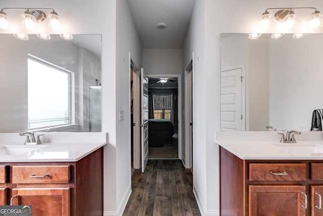 ensuite bathroom with ensuite bathroom, wood finished floors, vanity, baseboards, and walk in shower