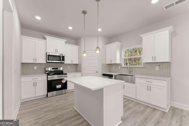 kitchen with visible vents, stainless steel appliances, light countertops, white cabinetry, and a sink