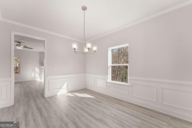 unfurnished dining area with a chandelier, wainscoting, light wood-type flooring, and crown molding