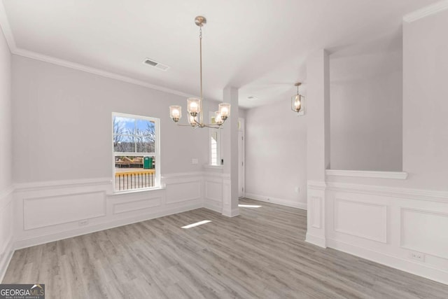 unfurnished dining area featuring visible vents, crown molding, an inviting chandelier, and wood finished floors