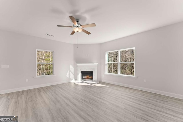 unfurnished living room featuring light wood finished floors, visible vents, a fireplace, and baseboards