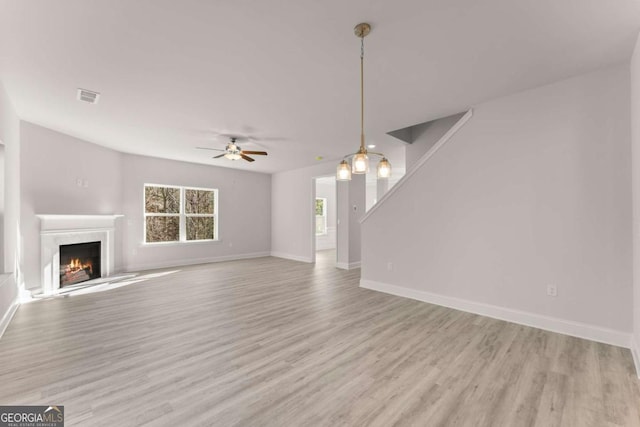 unfurnished living room featuring a premium fireplace, wood finished floors, visible vents, and baseboards