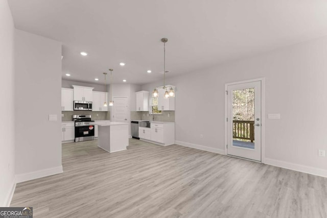 kitchen featuring open floor plan, stainless steel appliances, backsplash, and white cabinets