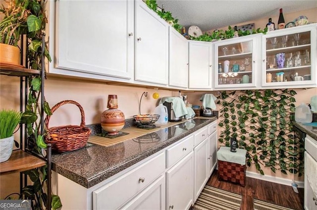 kitchen featuring glass insert cabinets, dark stone counters, white cabinets, and dark wood-style floors