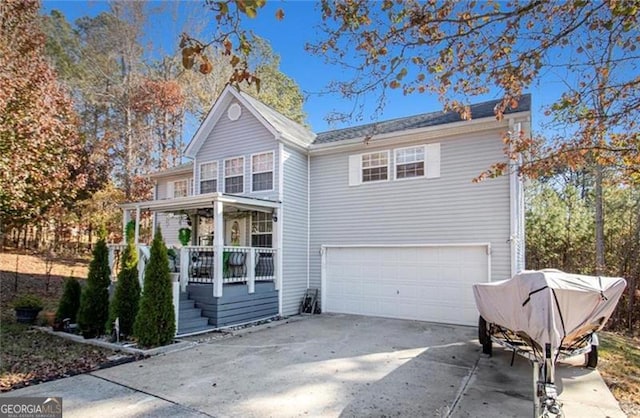 traditional home with a porch, concrete driveway, and a garage