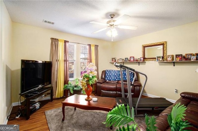 living area featuring visible vents, ceiling fan, a textured ceiling, wood finished floors, and baseboards