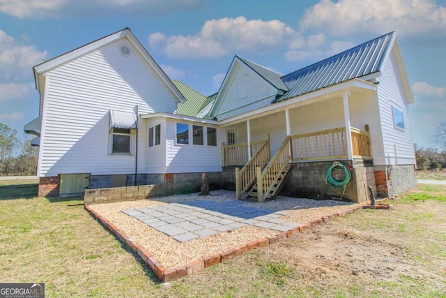 rear view of house featuring metal roof and a yard