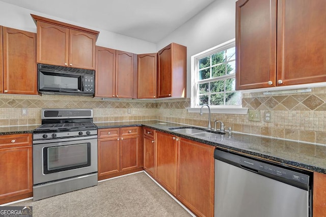 kitchen featuring backsplash, dark stone counters, stainless steel appliances, and a sink