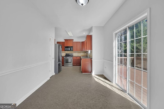 kitchen featuring baseboards, stainless steel appliances, a sink, and decorative backsplash