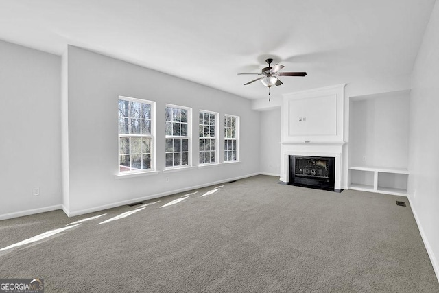 unfurnished living room with a fireplace, visible vents, a ceiling fan, carpet flooring, and baseboards