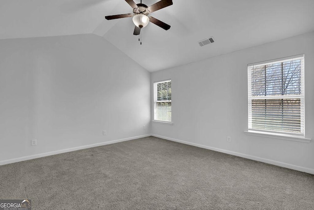 carpeted spare room with a ceiling fan, lofted ceiling, visible vents, and baseboards