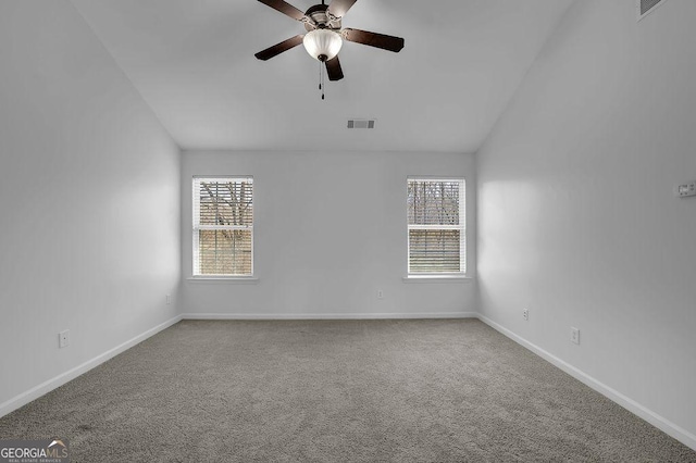 carpeted empty room with vaulted ceiling, visible vents, ceiling fan, and baseboards