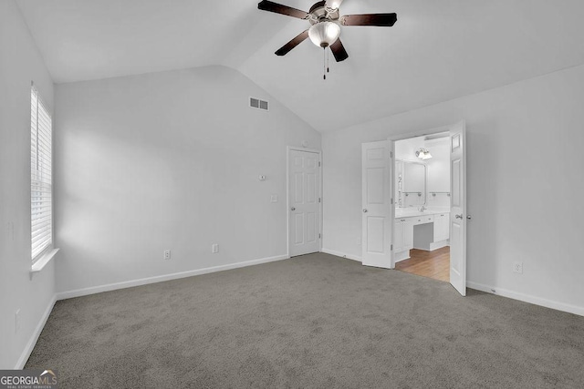 unfurnished bedroom with vaulted ceiling, carpet floors, multiple windows, and visible vents