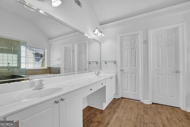 bathroom featuring lofted ceiling, visible vents, a sink, and wood finished floors