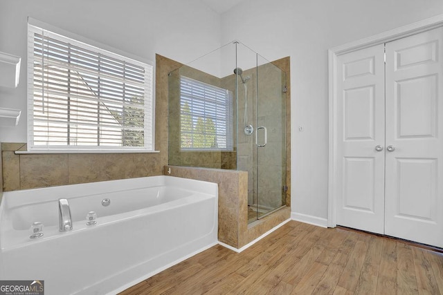 full bathroom with baseboards, wood finished floors, a bath, and a shower stall