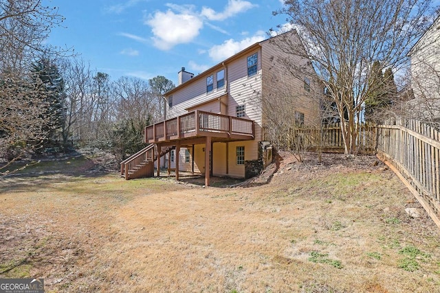 back of property with a deck, stairway, a chimney, and a fenced backyard