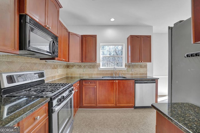 kitchen featuring recessed lighting, backsplash, appliances with stainless steel finishes, a sink, and dark stone counters