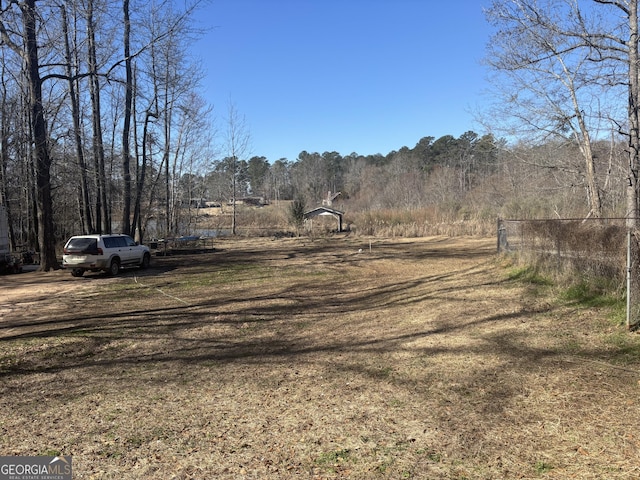 view of yard with a forest view and fence