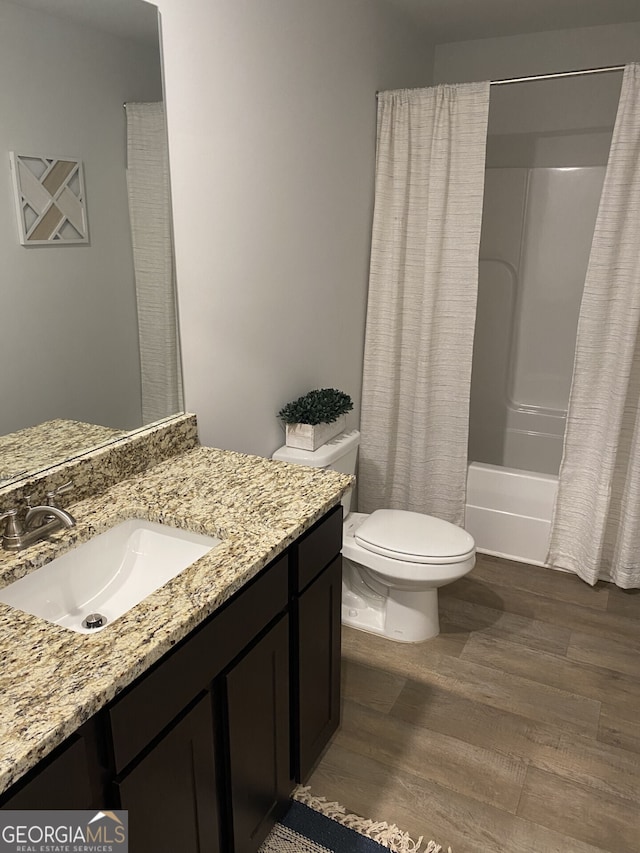 bathroom featuring shower / bathtub combination with curtain, vanity, toilet, and wood finished floors