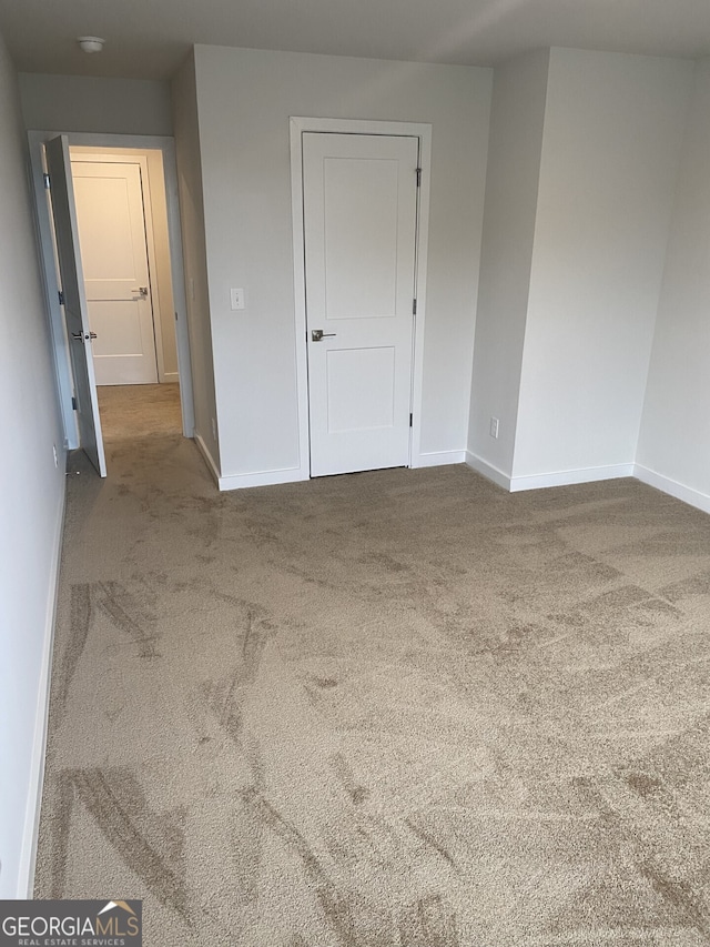 carpeted empty room featuring baseboards