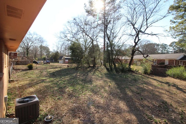 view of yard with visible vents, fence, and central AC