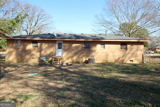 back of house with brick siding, crawl space, a lawn, and central air condition unit