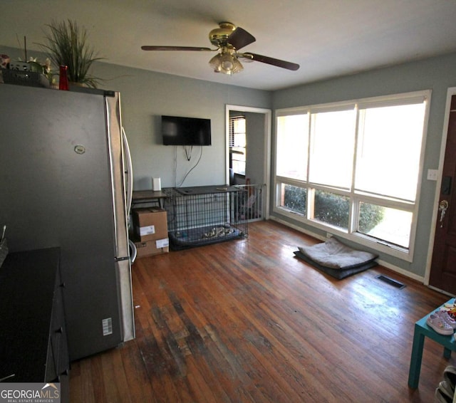 interior space with hardwood / wood-style flooring, baseboards, visible vents, and a ceiling fan