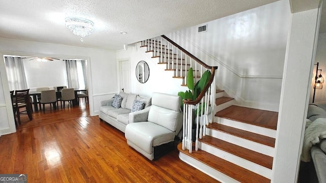 living area with visible vents, stairway, a textured ceiling, and wood finished floors