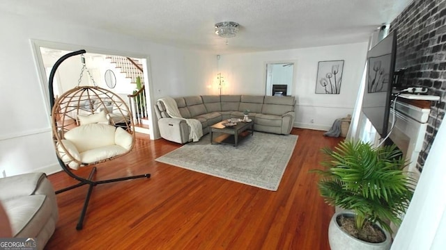 living room featuring baseboards, stairway, and wood finished floors