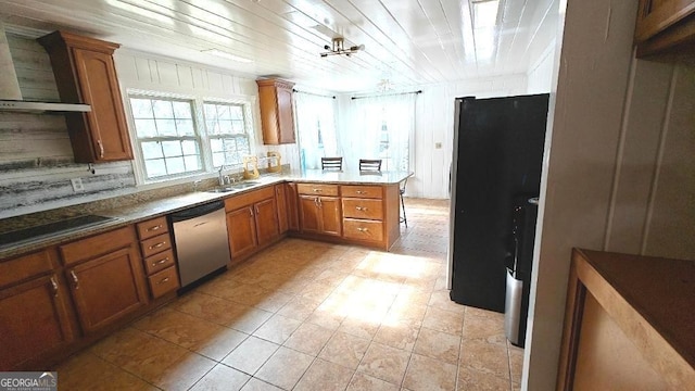 kitchen featuring black electric stovetop, stainless steel dishwasher, brown cabinetry, freestanding refrigerator, and a sink