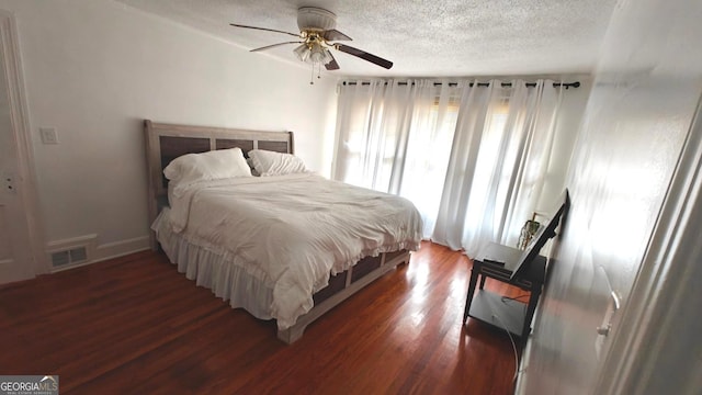 bedroom with ceiling fan, a textured ceiling, visible vents, and dark wood-type flooring