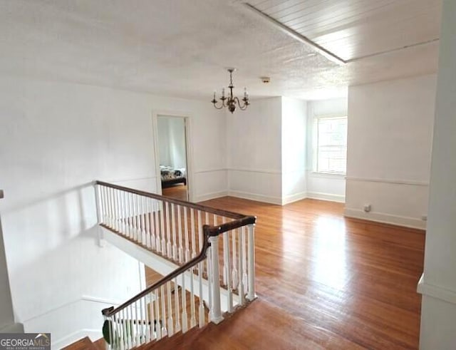 empty room featuring baseboards, wood finished floors, and an inviting chandelier